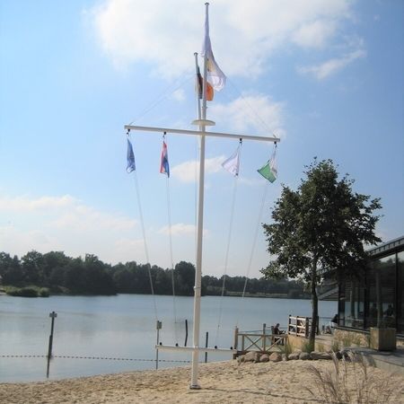 Ein Signalmast am Ufer eines Gewässers mit mehreren Fahnen