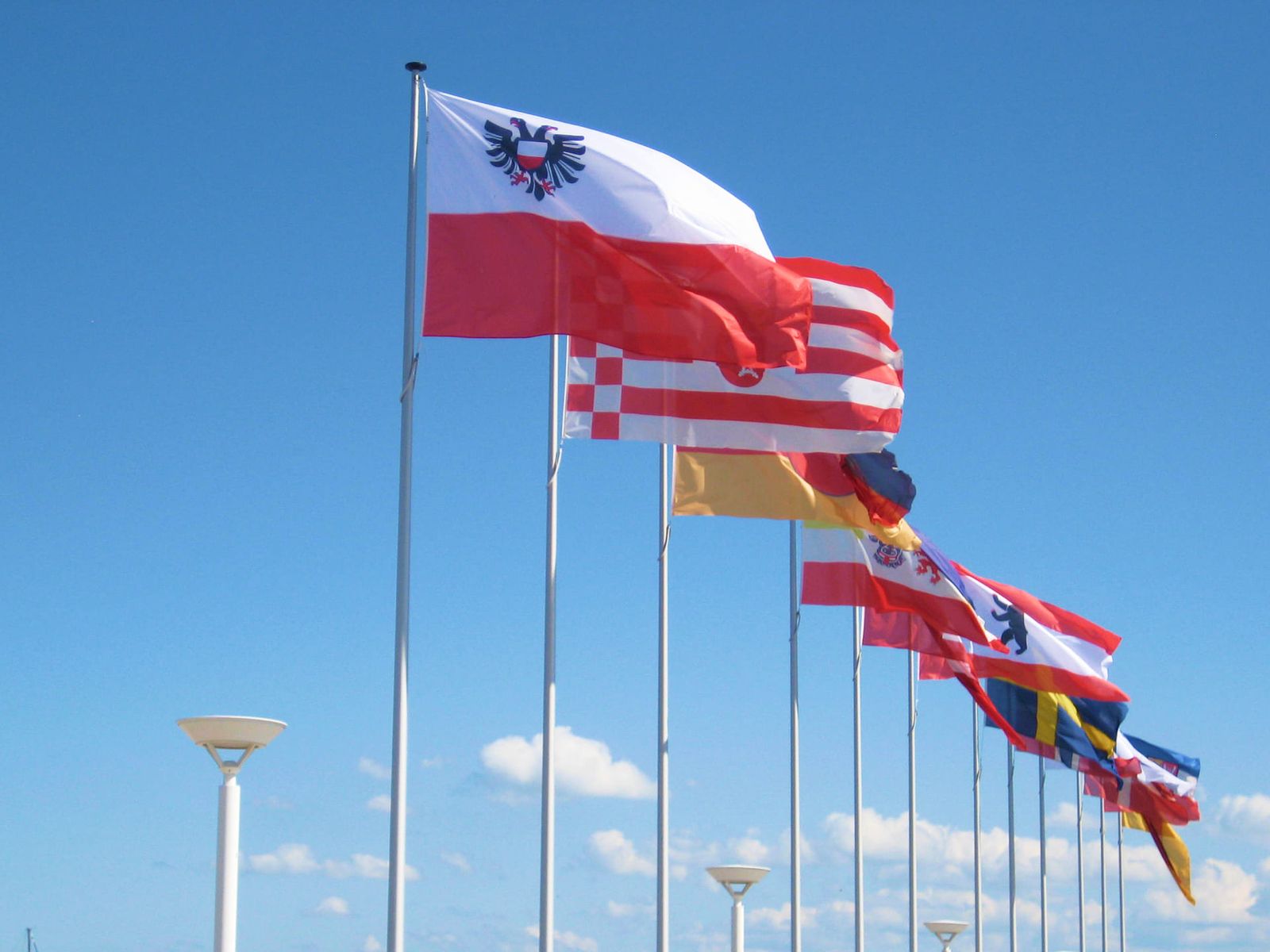 Fahnen von europäischen Ländern wehen im Wind vor blauem Himmel im Hintergrund