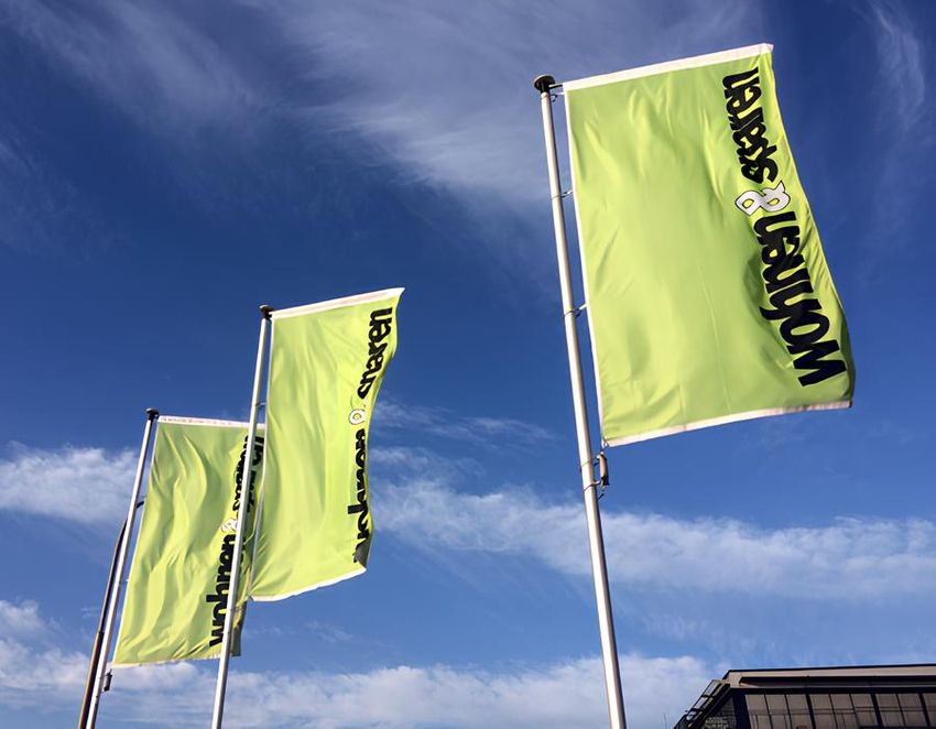 Gelbe Fahnen mit Aufschrift von Fahnen Reichel System vor blauem Himmel im Hintergrund