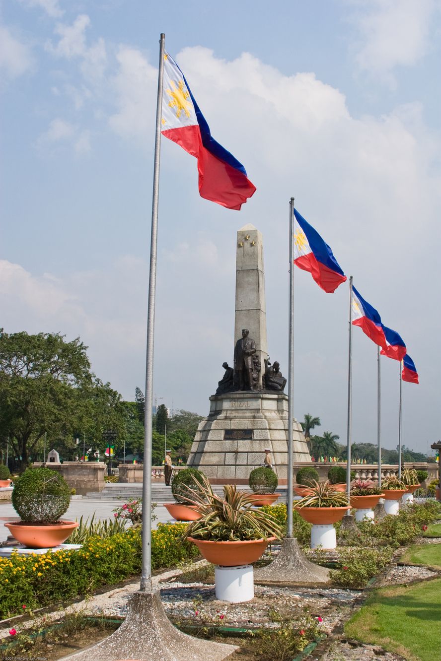 Mehrere Landesflaggen an Fahnenmästen in einem Garten eines großen Anwesens