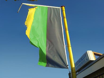 Eine Fahne an einem Fahnenmast in den Farben Gelb, Grün und Schwarz